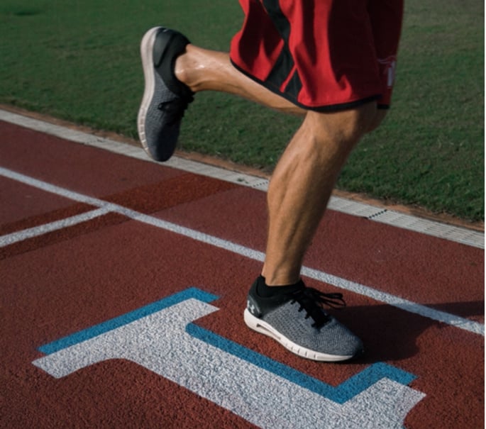 legs of male athlete running on a track